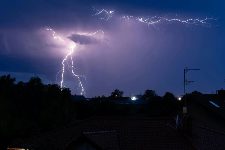 lightning striking over houses in an urban area