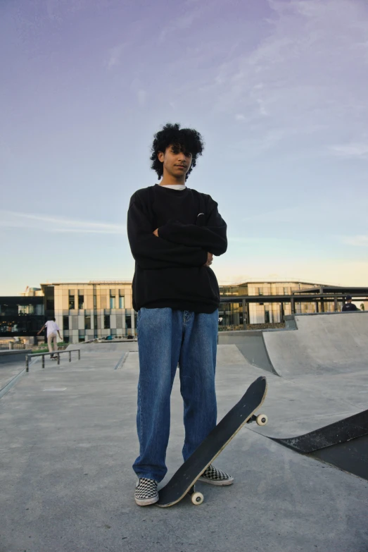 man in black sweater standing on skateboard with his hands crossed