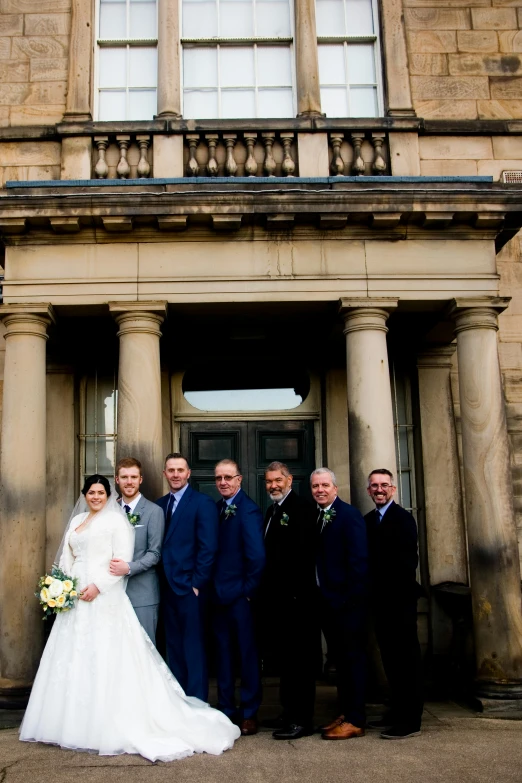 a bride and groom posing with their three friends outside a church