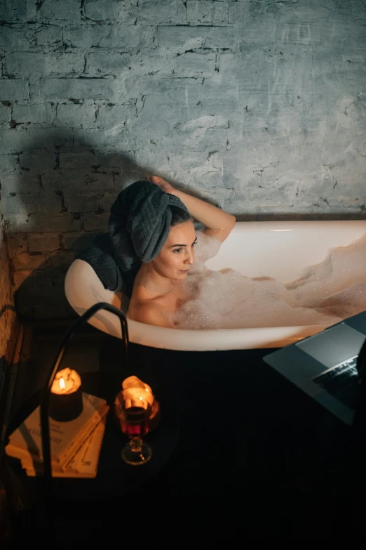 a woman sitting in a bathtub with her back to the camera