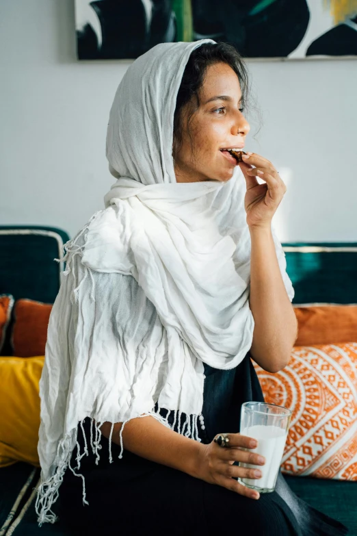 a woman sitting on a couch taking a bite out of soing