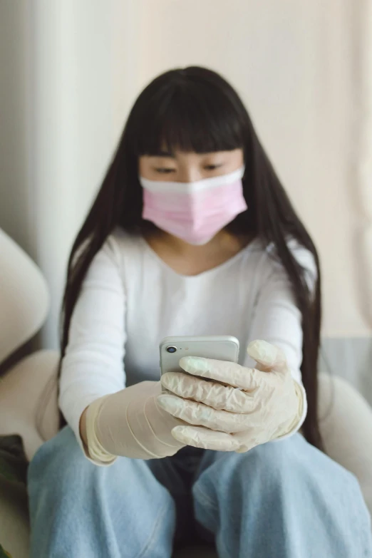 a woman wearing a surgical mask while using a cell phone