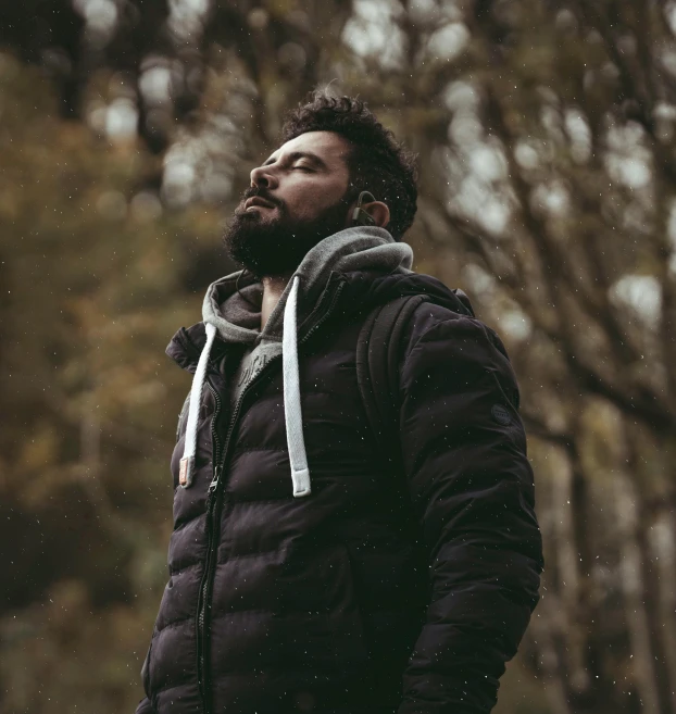 a man with black and grey jacket in the woods