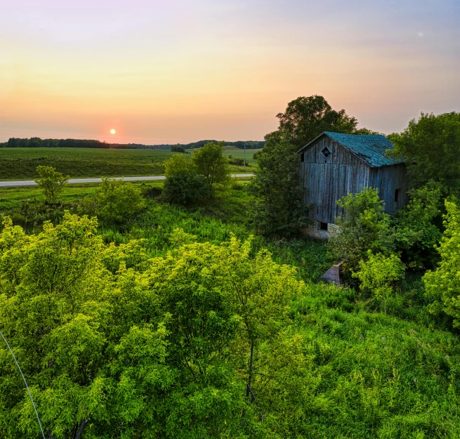 the sun setting behind a large old building in the middle of a wooded area