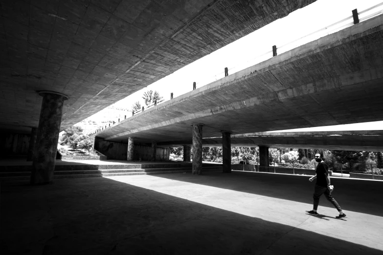 a person skateboards under an overpass in black and white