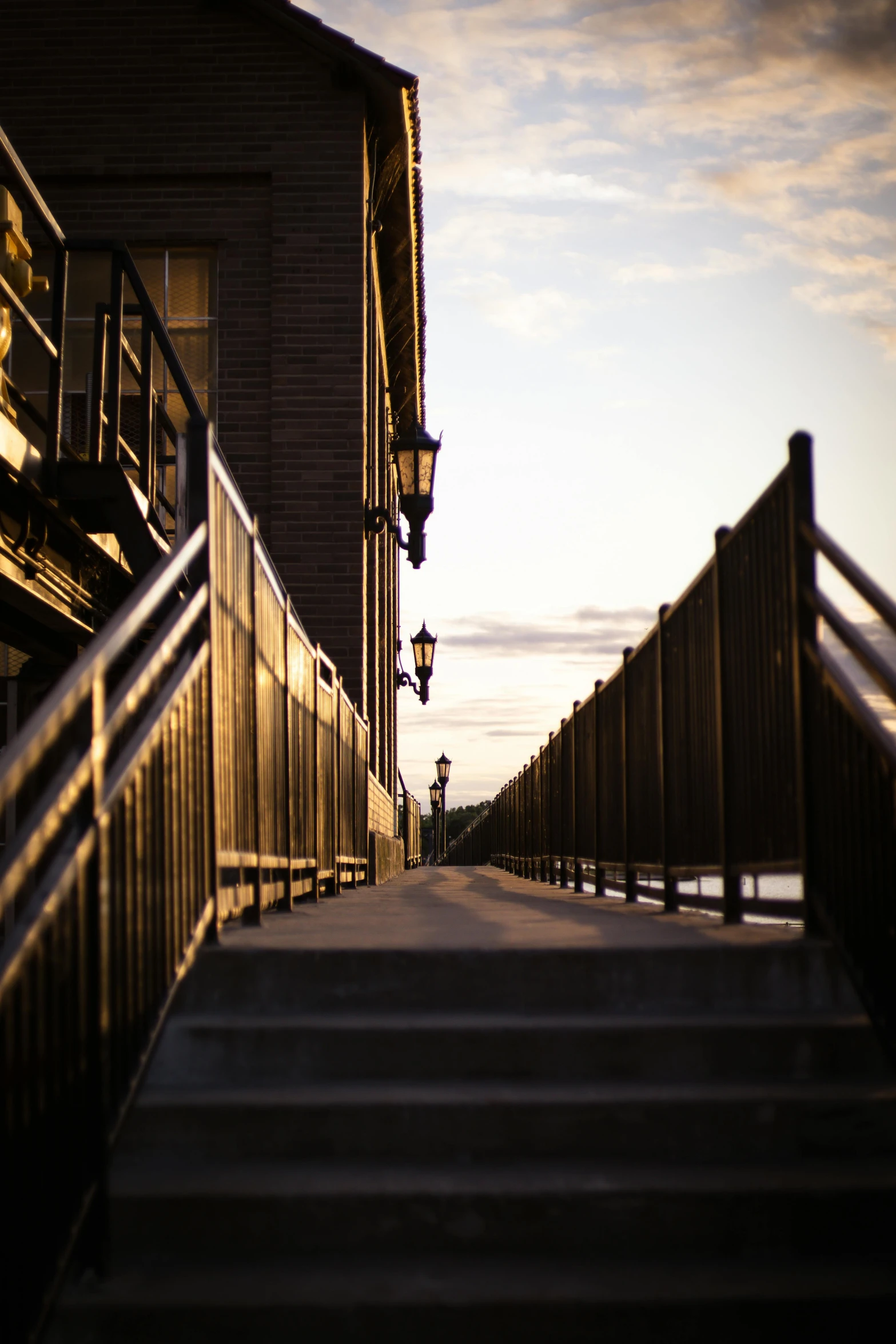 a walkway with metal railing and stairs next to some buildings