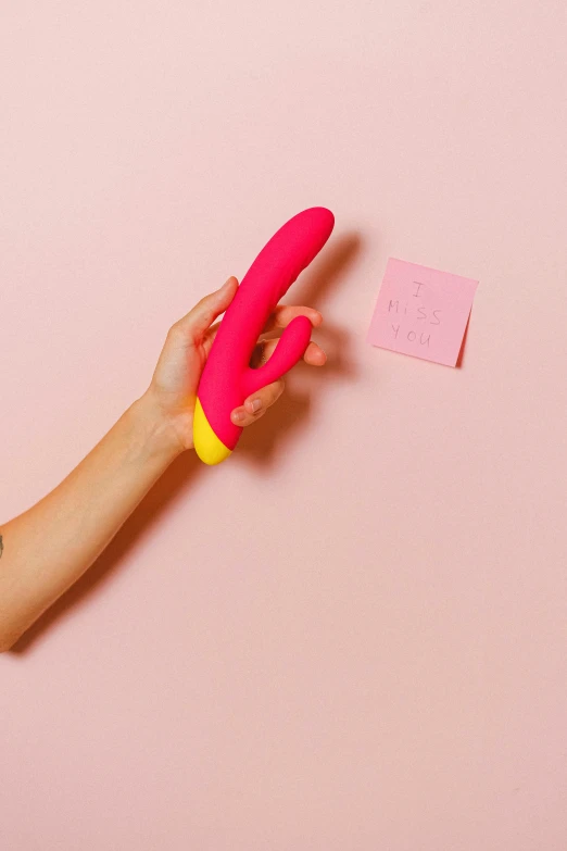 a hand holding up a pink toy to a pink paper stuck in it