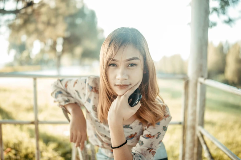 a young woman is sitting on a bench talking on a cell phone