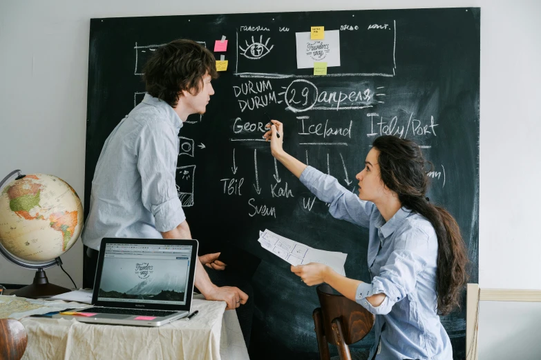 two people writing on the blackboard in an office