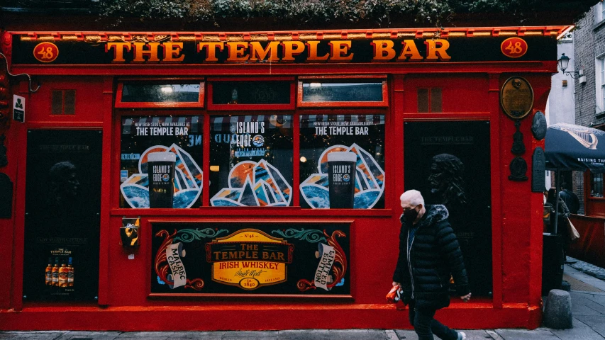 a man walks past an outdoor temple bar