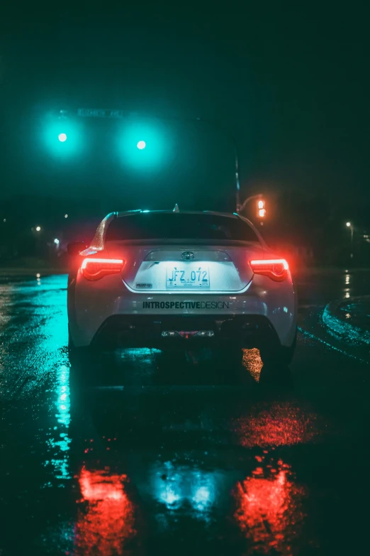 cars stopped at a traffic light on a rainy night