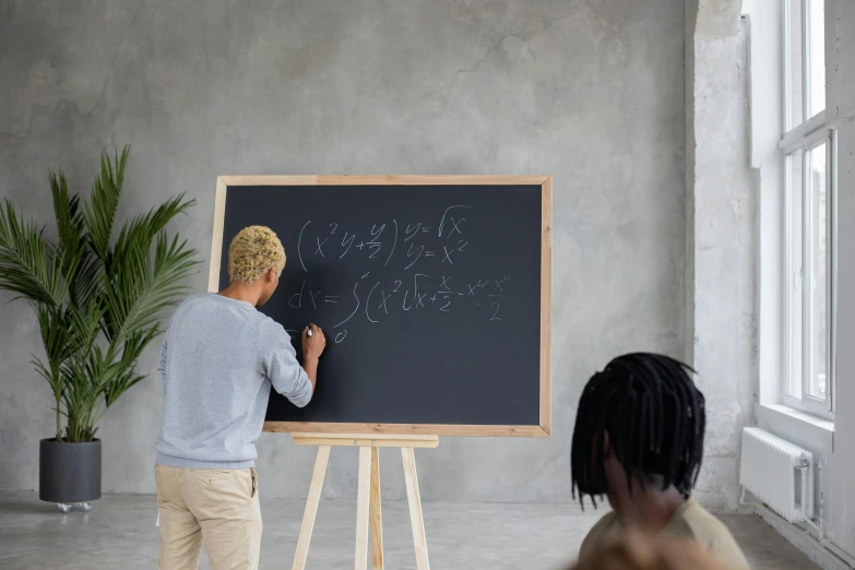 there is a boy that is writing on a chalk board