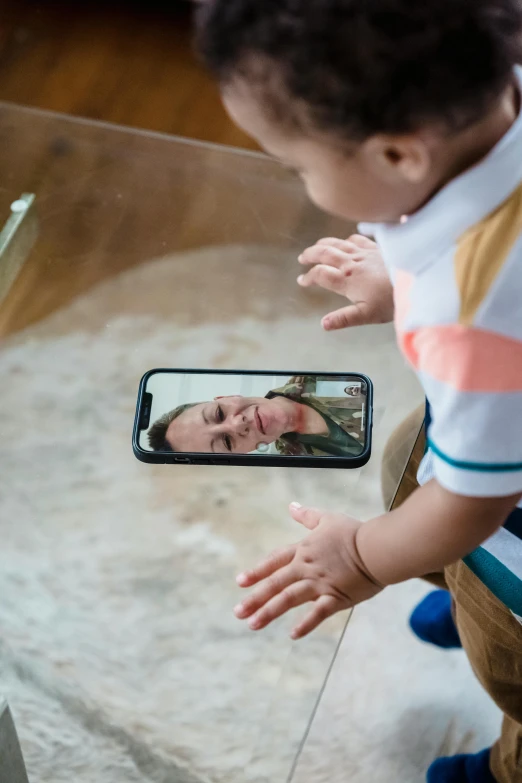 a child is taking a picture of a cell phone being held by a woman