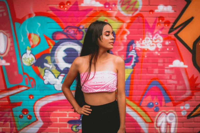 a woman stands in front of a colorful wall