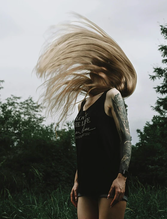 a woman with a tattoo on her arm is blowing her hair