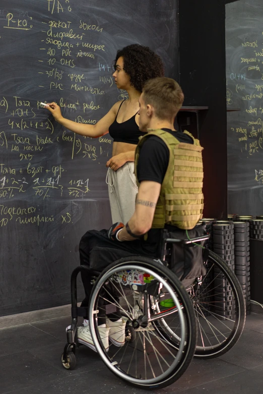 a man in a wheelchair writing on a chalkboard