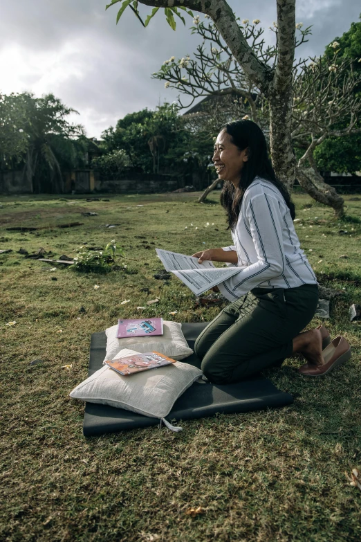 a woman sitting in the grass and looking at some news