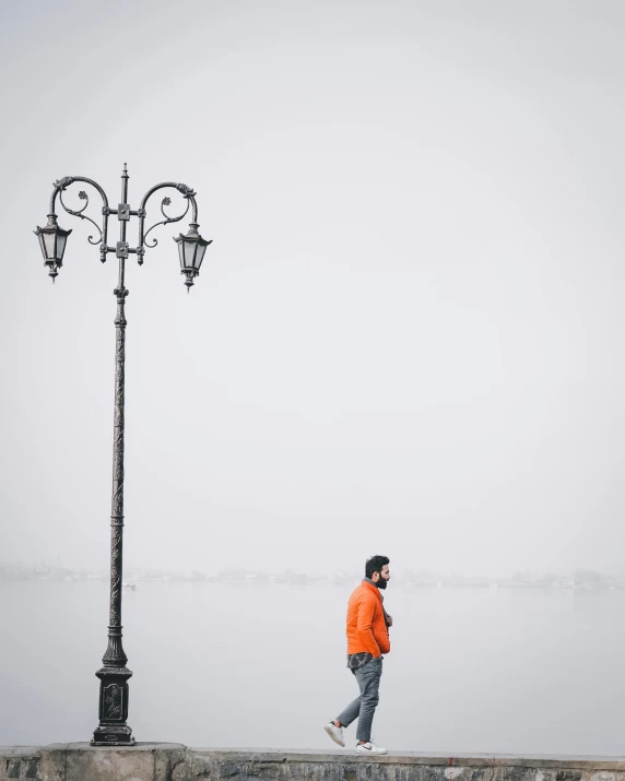 a man walking along side the water while holding a cell phone