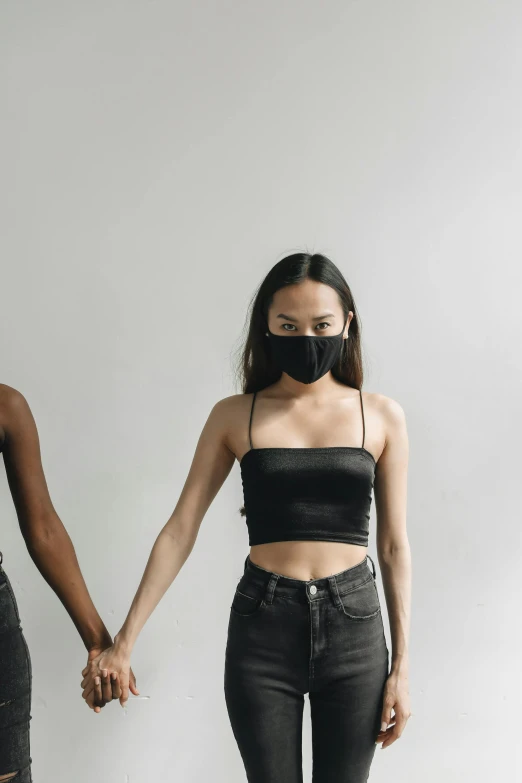 two young ladies holding hands in front of a white wall