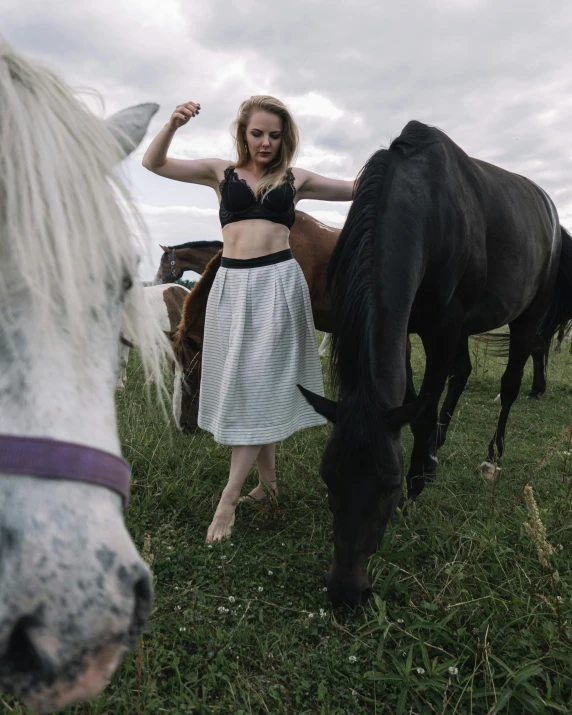 woman in dress next to a horse on grass field