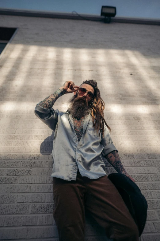 a man with a beard and sunglasses sitting on top of a brick wall