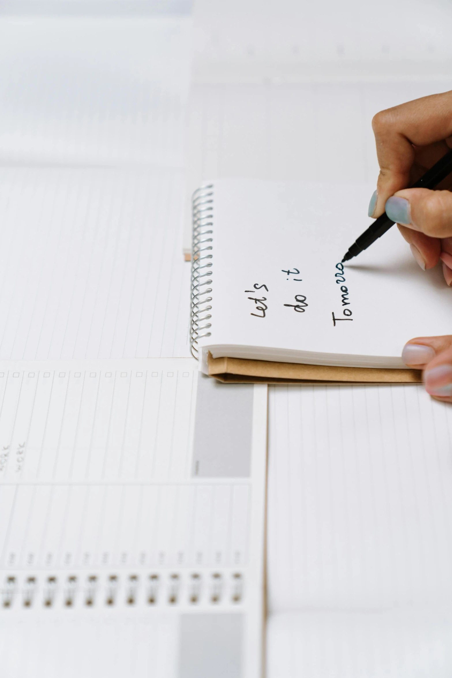 a woman writing on a note pad while sitting at a table