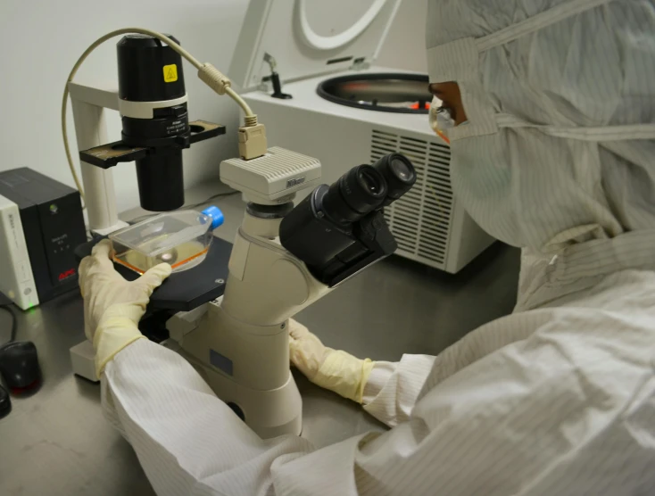 a man wearing protective clothing sitting in a lab