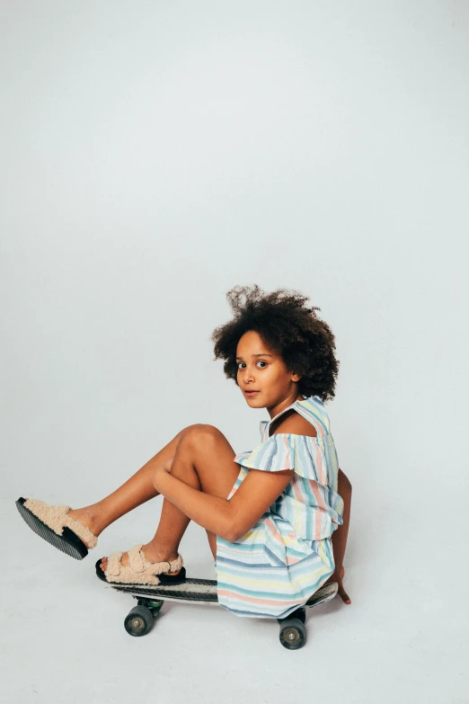 a  sits on the back of her skateboard