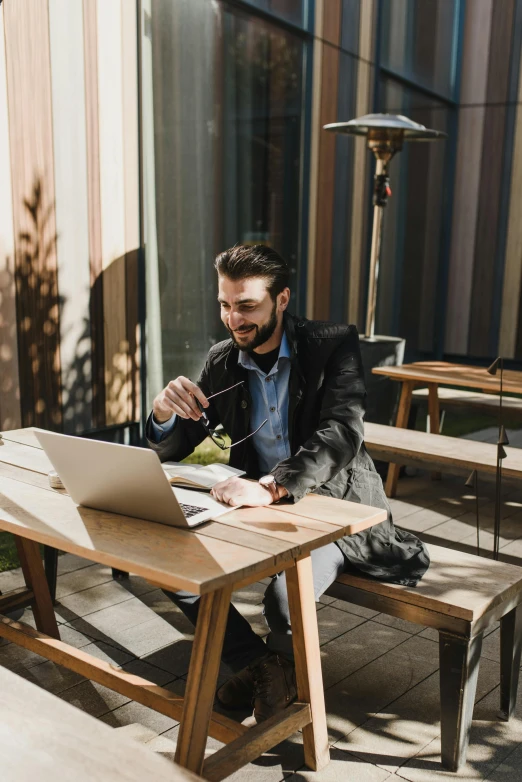 man sitting at table with his laptop and cup on the ground