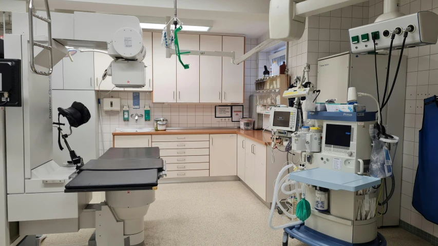 a medical room with machines, tables and cabinets