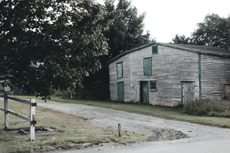 a rustic looking building in the countryside, near a fence