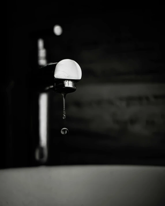 this black and white po shows a close up of a water faucet with soap in it