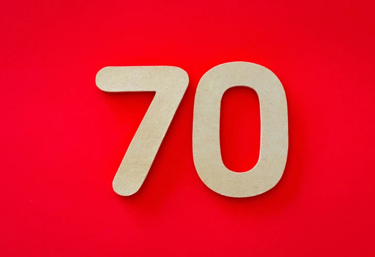 a wooden number seventy cutout on a red background