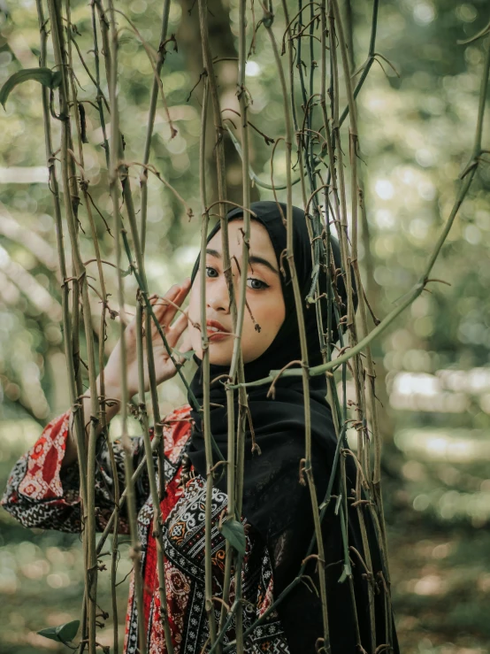 the woman in a scarf stands under nches of trees