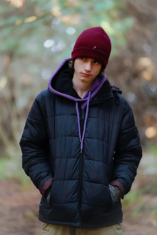 young man with red hat and black coat standing outdoors