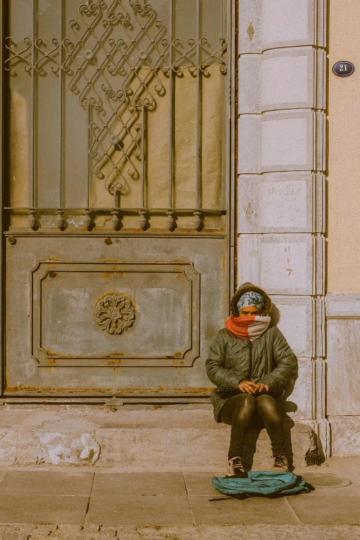 a boy in winter coat sitting on a sidewalk