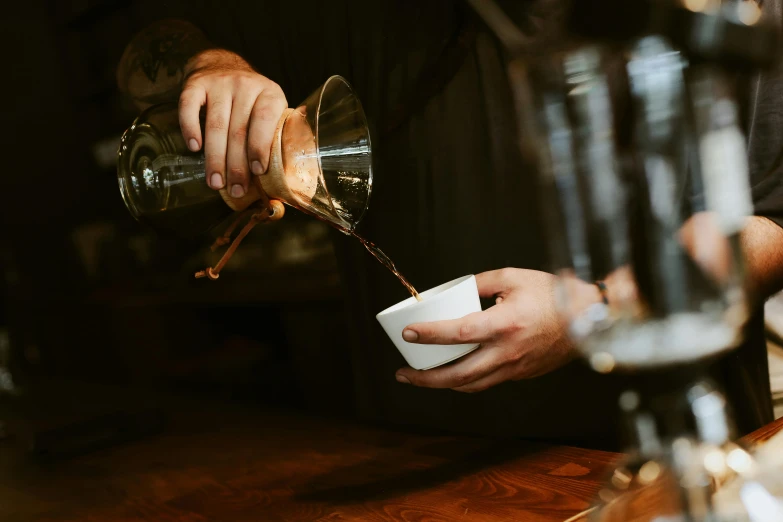 the bartender pours his drink into a cup