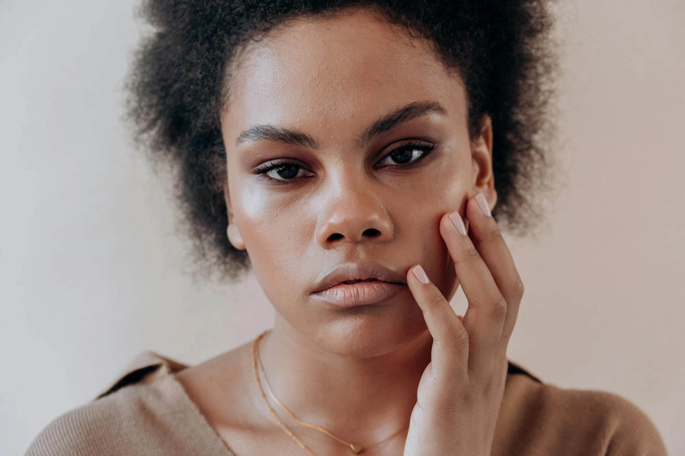 a woman is holding her hand up to her face