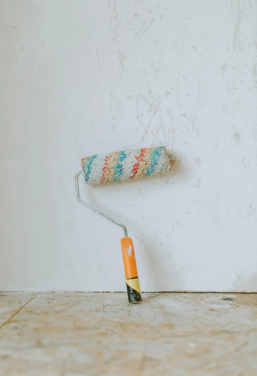 a po of a painted wall and a roller on the floor