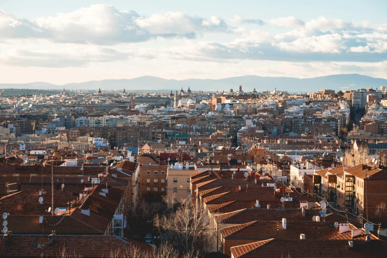 a city skyline with roofs and mountains in the distance