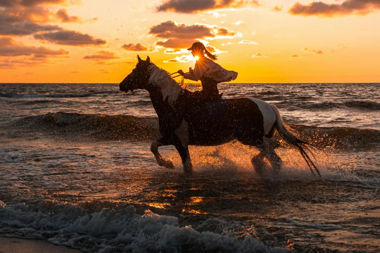 woman riding a horse on the beach during sunset