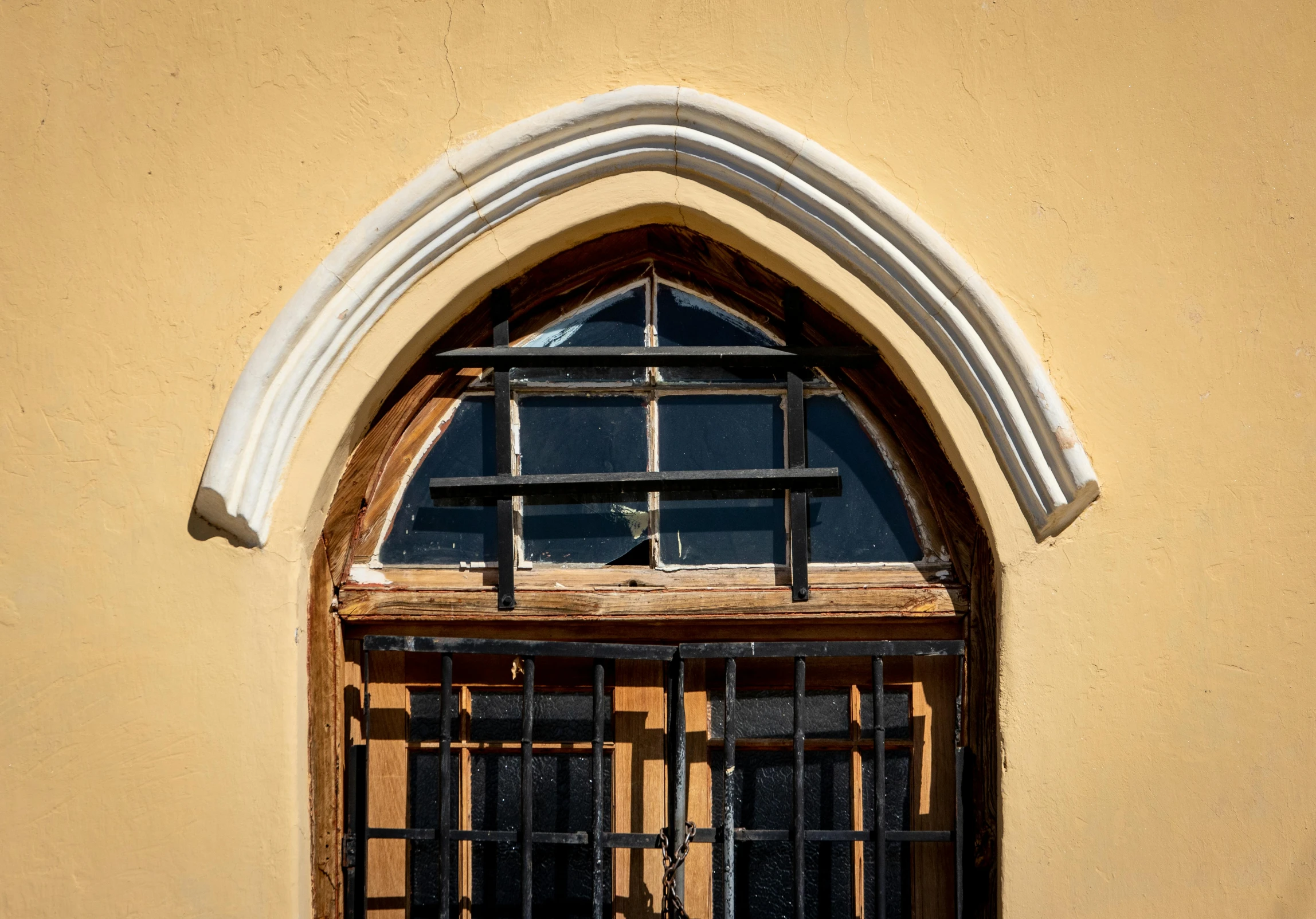 an arched window with bars and an iron gate