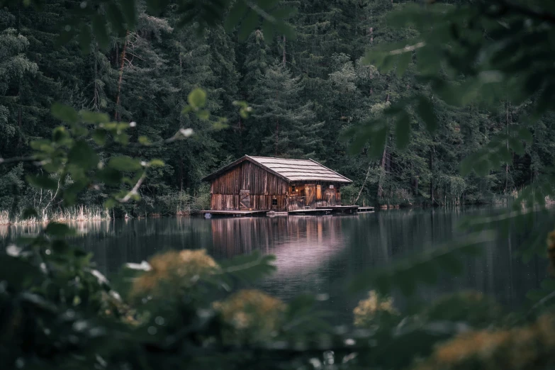 an old boathouse sitting in the middle of a lake
