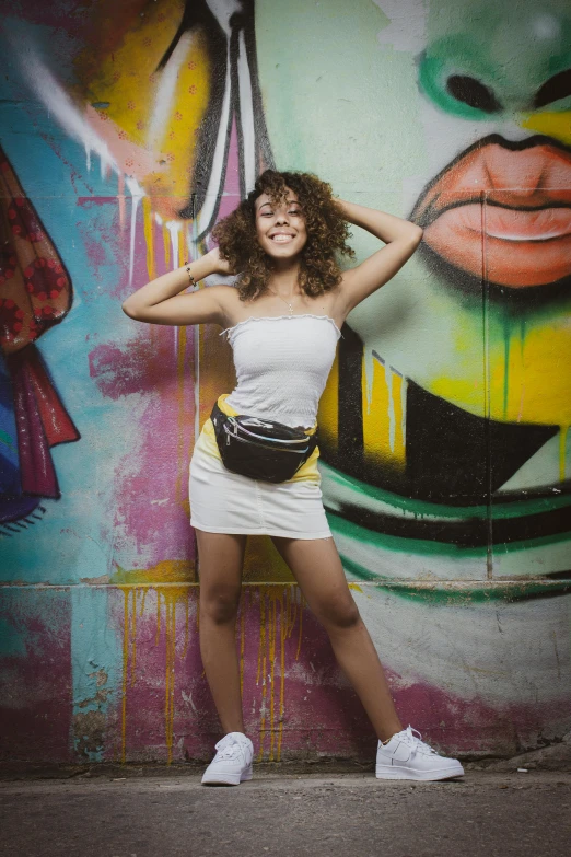 woman in white dress standing near graffiti on wall