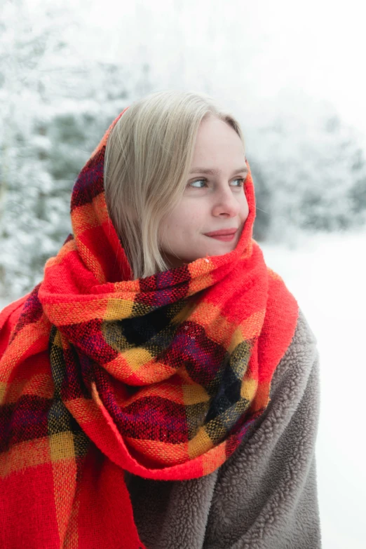 the woman wearing a red and yellow scarf looks off into the distance