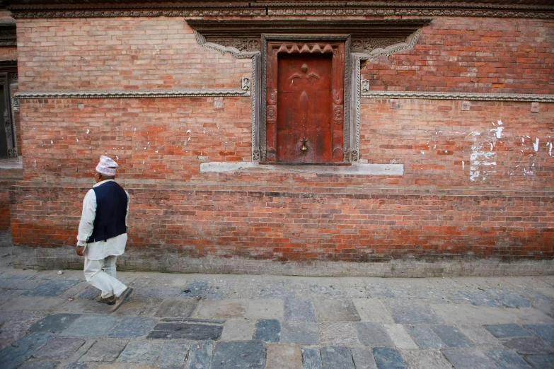 a person walking by a door in a brick wall