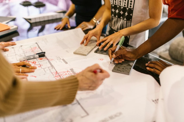 several people are discussing some blueprint while sitting at a table