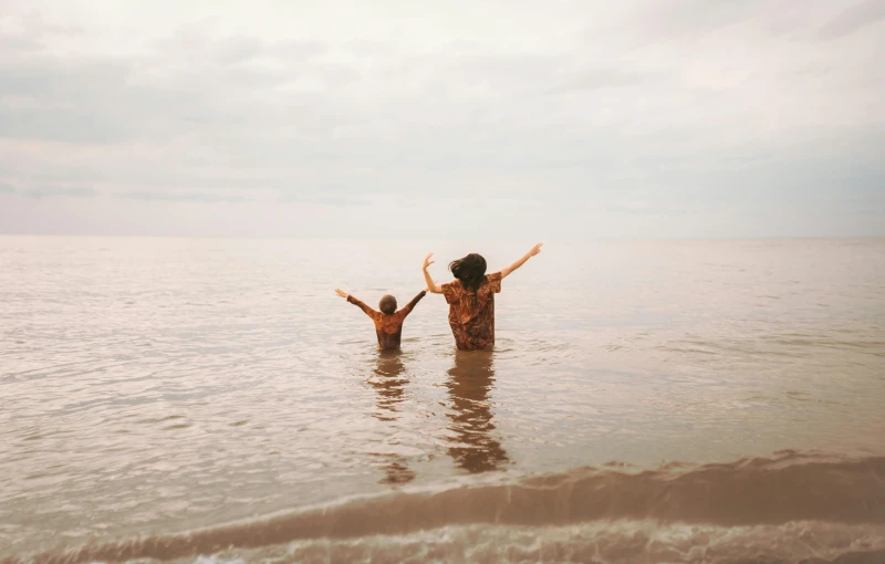 two people standing in the ocean holding hands