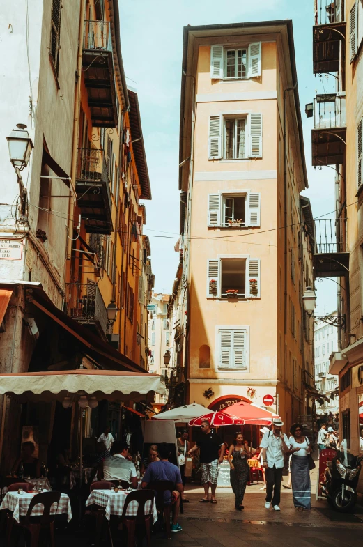 several people walking down an alley lined with buildings