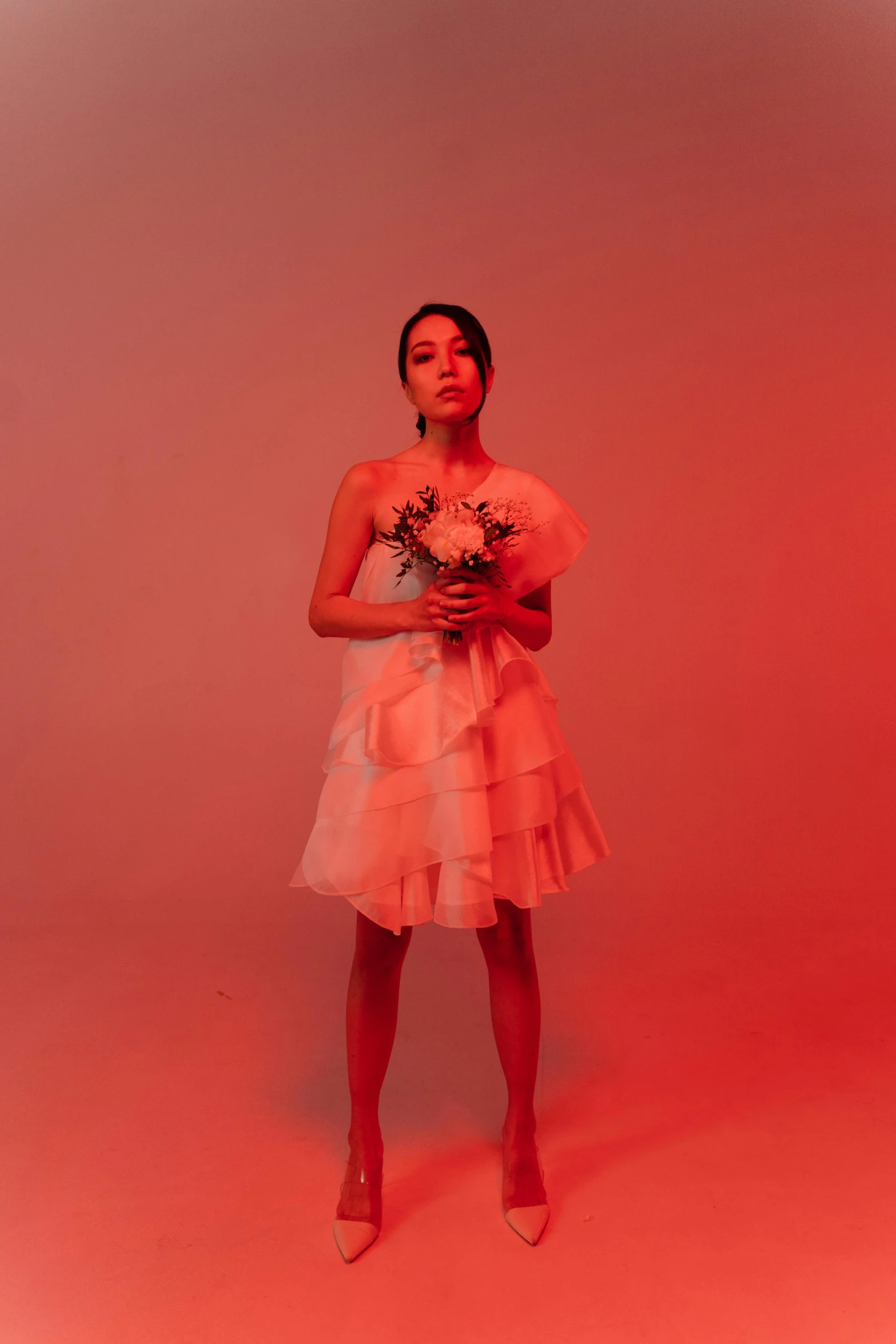 a girl standing against a red backdrop in a dress